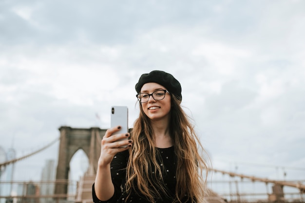 Femme joyeuse prenant un selfie avec le pont de Brooklyn, USA