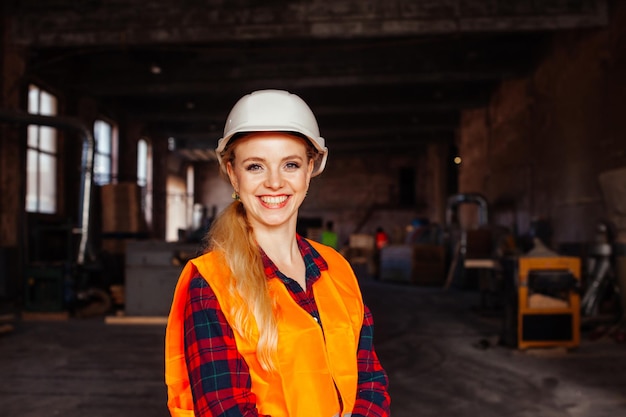 La femme joyeuse regarde l'appareil-photo dans l'usine