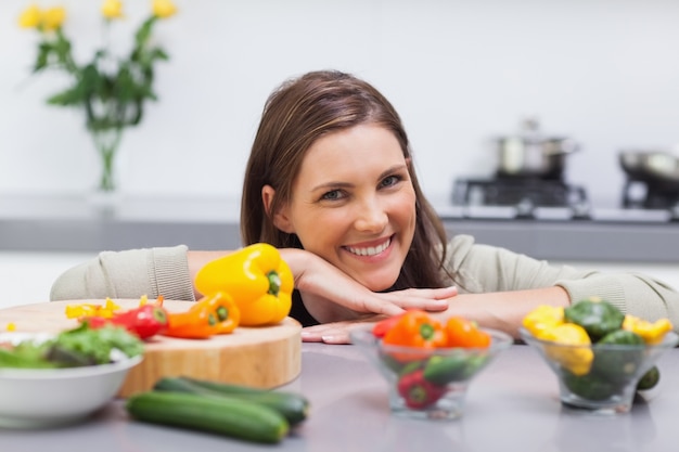 Femme joyeuse s&#39;appuyant sur le comptoir de sa cuisine