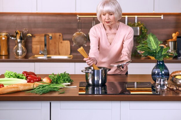 femme joyeuse senior cuisine dans une cuisine moderne