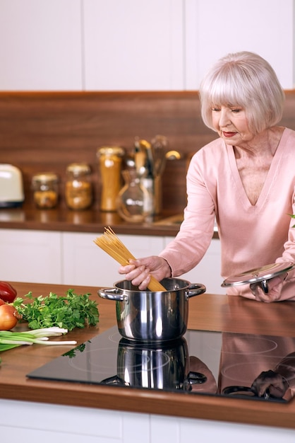 femme joyeuse senior cuisine dans une cuisine moderne