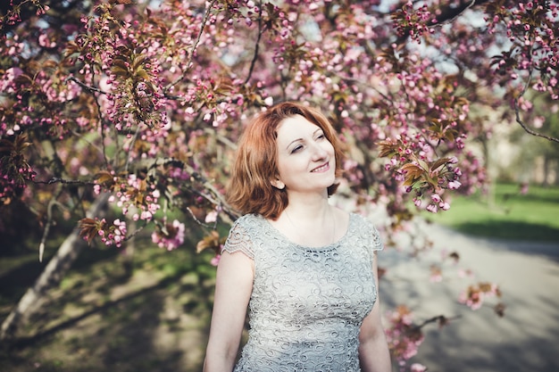 Femme joyeuse sous l'arbre en fleurs de sakura.