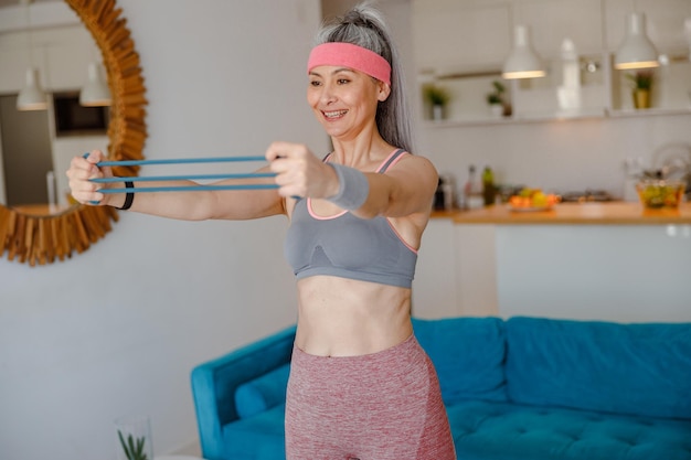 Femme joyeuse utilisant une bande de résistance des bras pendant l'entraînement à domicile