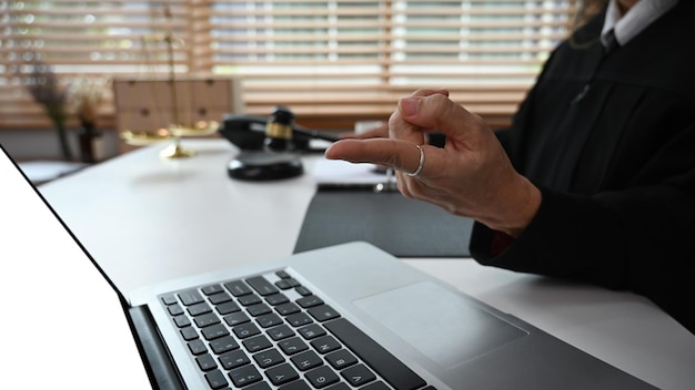 Femme juge ou avocate mature assise devant un ordinateur portable offrant une consultation juridique en ligne sur le site Web