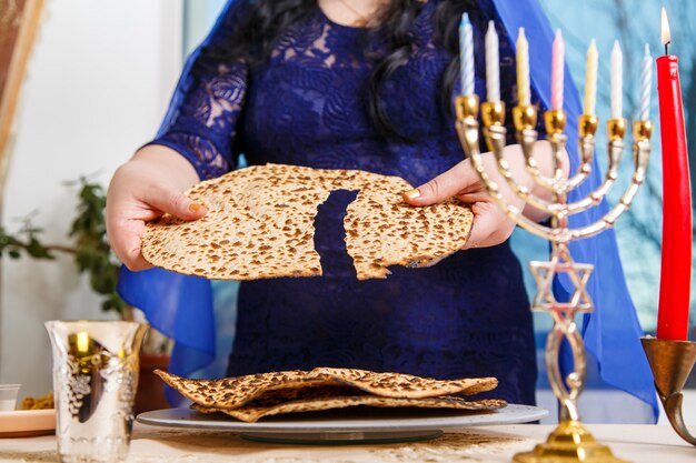 Une femme juive à la table du Seder de la Pâque brise la shmura matzah. Photo horizontale