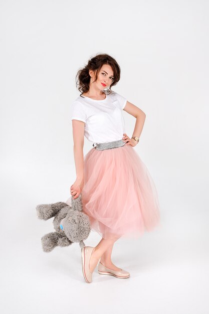 Femme en jupe rose tenant un gros ours en peluche doux