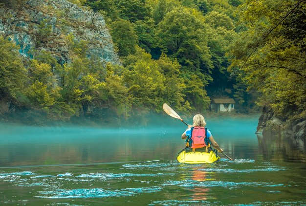 Photo femme en kayak dans le brouillard sur le lac de montagne