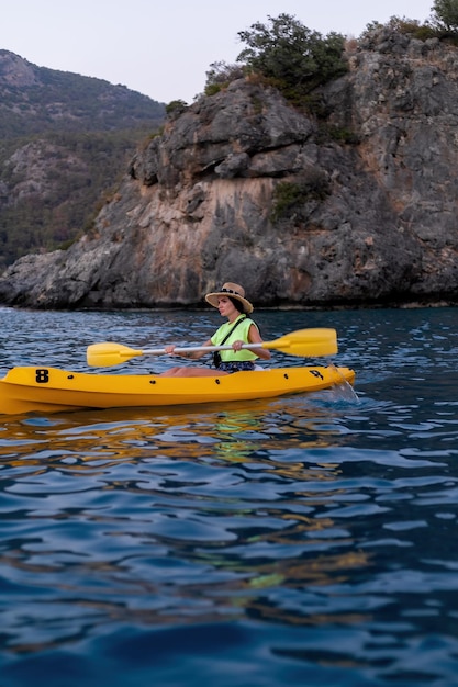 Femme de kayak s'amusant à faire du kayak dans une station balnéaire tropicale à Tahiti. Fille asiatique profitant des sports nautiques en vacances au coucher du soleil. Caméra d'action.