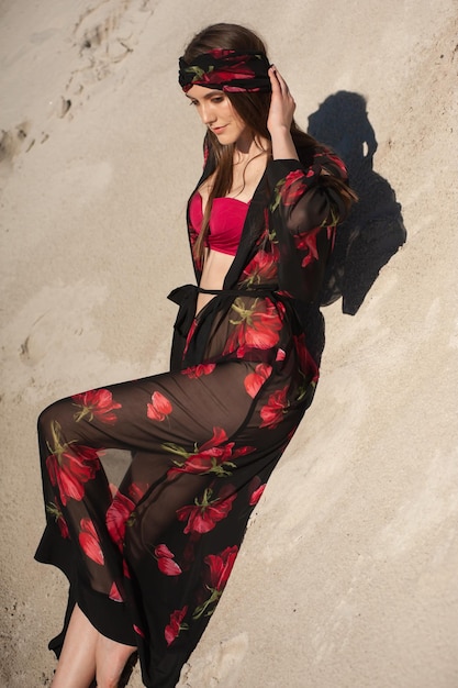 Une femme en kimono est allongée sur le sable et porte un imprimé de fleurs rouges.