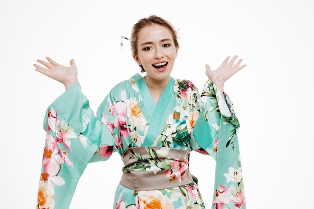 Femme en kimono japonais traditionnel heureux et surpris en levant les bras sur blanc