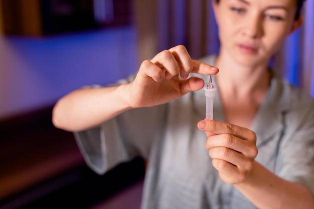 Femme laissant tomber du liquide sur une bandelette de test d'échantillon COVID19