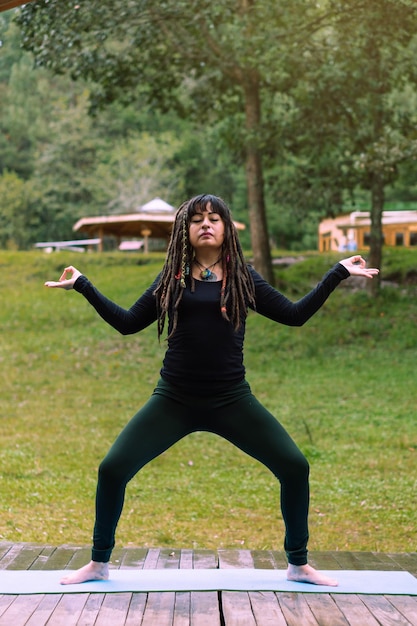 Femme Latina avec des dreadlocks en position de yoga.