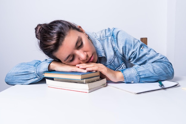 Femme latina étudiant à la maison assise endormie sur ses livres concept de collège de rêve