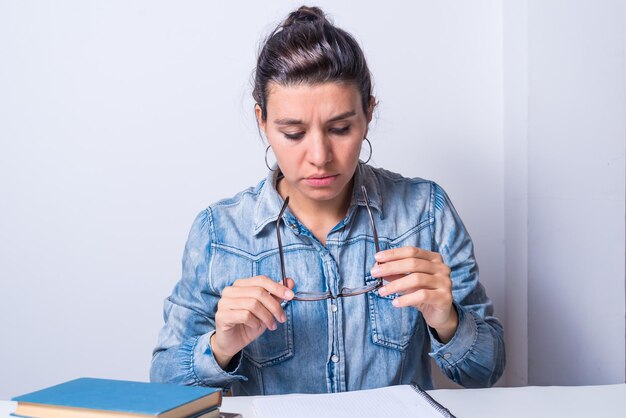 Femme latina étudiant à la maison assise en regardant ses lunettes concept de collège sérieux