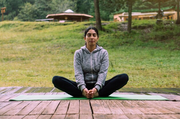 Femme latina portant des vêtements de sport, assise en position du lotus. Le bien-être.