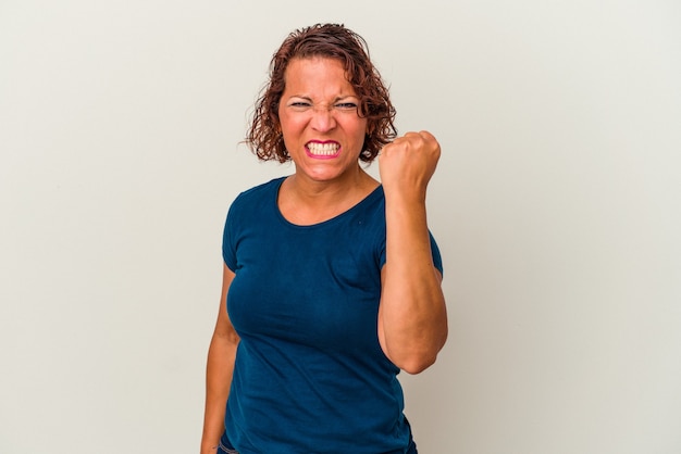 Femme latine d'âge moyen isolée sur fond blanc montrant le poing à la caméra, expression faciale agressive.