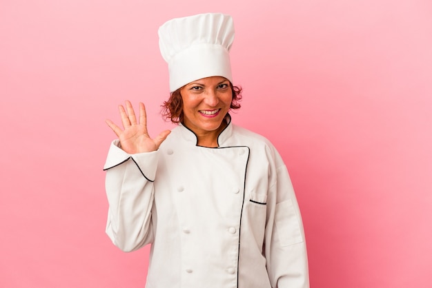 Femme latine d'âge moyen isolée sur fond rose souriante joyeuse montrant le numéro cinq avec les doigts.