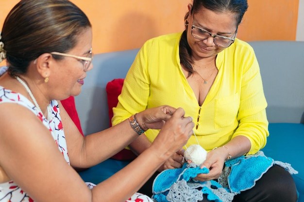 Femme latine apprenant à tricoter à sa sœur. Concept d'artisanat.