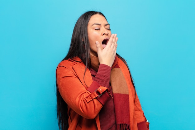 Femme latine bâillant paresseusement tôt le matin, se réveillant et l'air somnolent, fatigué et ennuyé