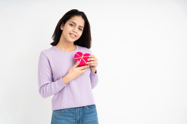 Femme latine avec boîte-cadeau en forme de coeur dans les mains sur fond blanc