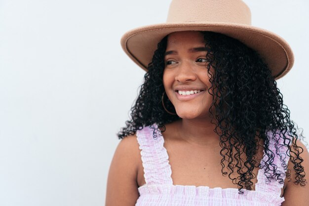 Femme latine avec chapeau sur un mur blanc