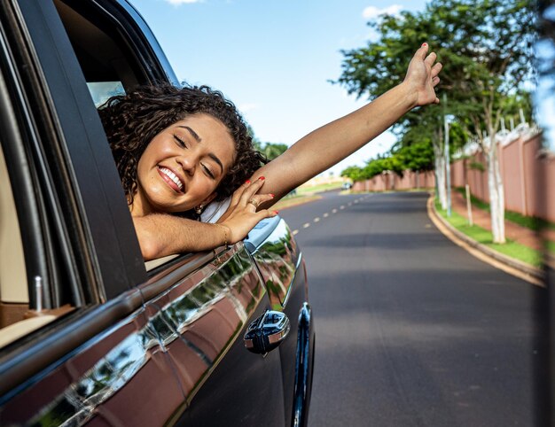 Femme latine dans la fenêtre de la voiture. Voyage en voiture. La fille regarde par la fenêtre de la voiture. Concept de voyage brésilien en voiture.