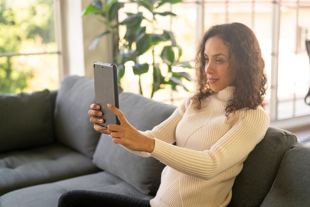 Femme latine facetime ou vidéoconférence sur tablette avec sentiment de bonheur