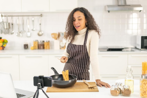 Femme latine filmant une vidéo et cuisinant dans la cuisine à partager sur le blog