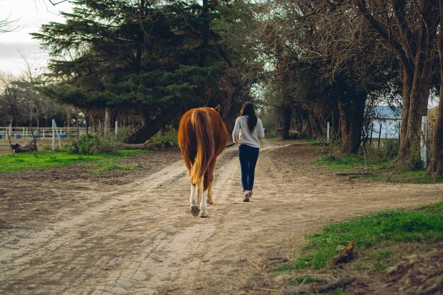 Photo une femme latine marche le long d'une route non pavée dans la campagne argentine en promenant son cheval