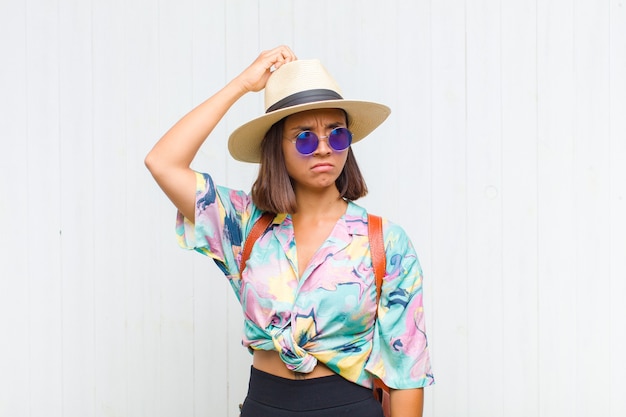 Femme latine perplexe et confuse, se gratte la tête et regarde sur le côté