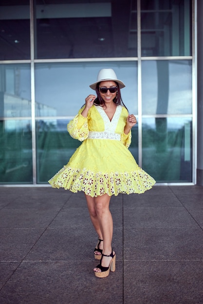 Femme latine en robe jaune dansant dans la rue.