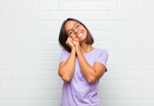 Femme latine se sentir amoureuse et à la mignonne, adorable et heureuse, souriant romantiquement avec les mains à côté du visage