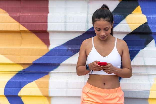 Femme latine avec son smartphone avant de courir. Concept de vie saine.