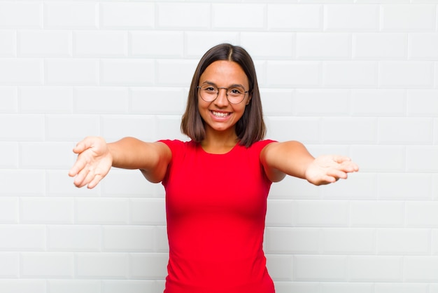 Femme latine souriant joyeusement donnant un câlin de bienvenue chaleureux, amical, aimant, se sentant heureux et adorable