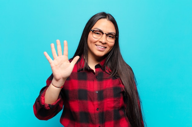 Femme latine souriante et à la recherche amicale, montrant le numéro cinq ou cinquième avec la main en avant, compte à rebours