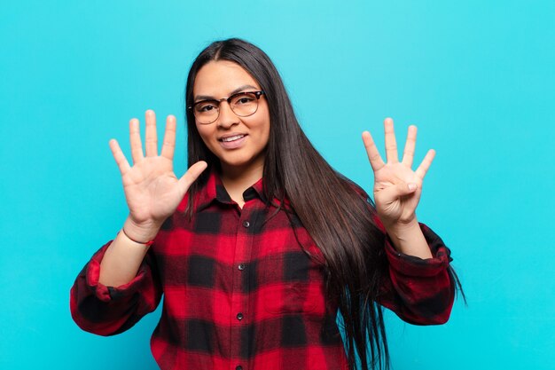 Femme latine souriante et à la sympathique, montrant le numéro neuf ou neuvième avec la main en avant