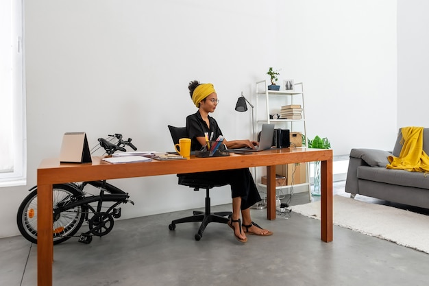 Femme latine travaillant au bureau à domicile avec ordinateur portable et documents