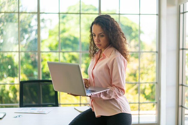 Femme latine travaillant avec un ordinateur portable sur un espace de travail à la maison