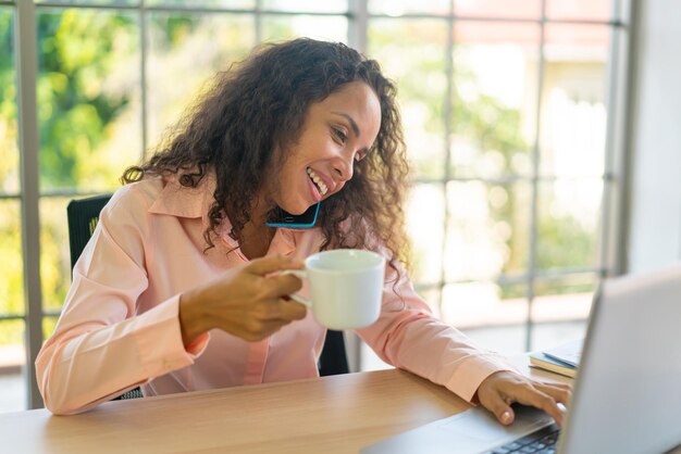 Femme latine travaillant avec une tasse de café sur un espace de travail à la maison
