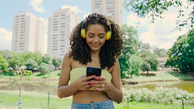 Femme latine utilisant un smartphone dans le parc. Brésilienne.