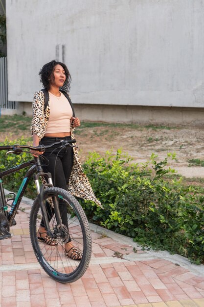 Une femme latine avec un vélo en milieu urbain