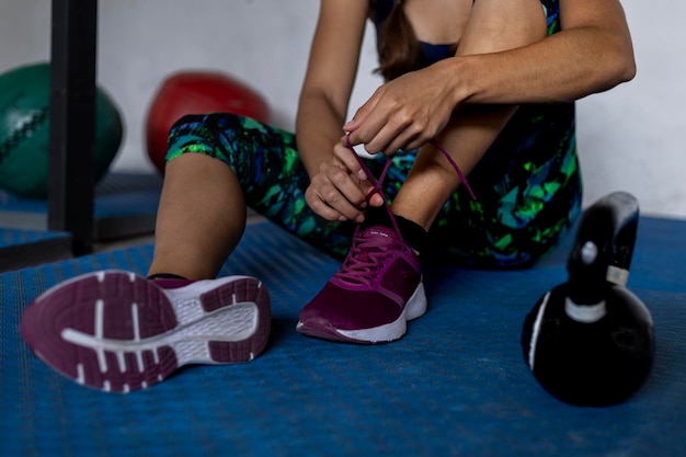 Une femme latino-américaine méconnaissable est assise à attacher les tresses de ses chaussures à la salle de sport Concept de mode de vie sain