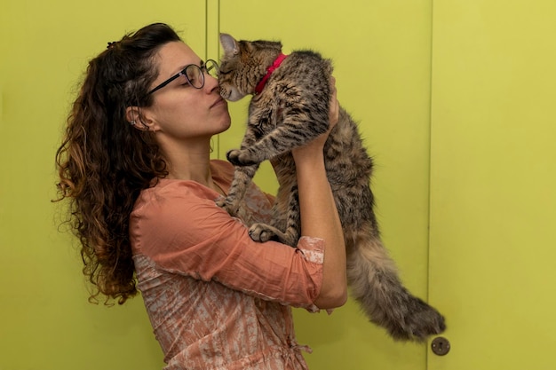 Une femme latino-américaine tient dans ses bras et joue affectueusement avec son chat