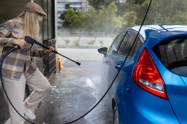 Femme lavant une voiture dans une station de lavage de voiture en libre-service avec de la mousse de lavage Station de lavage de voiture en libre-service