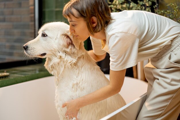 Une femme lave son chien dans une baignoire à la maison