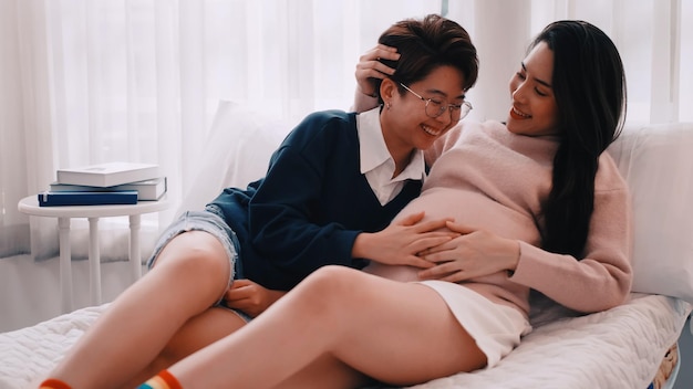 Une femme lesbienne asiatique enceinte et son partenaire sont heureux de passer du temps ensemble à la maison.