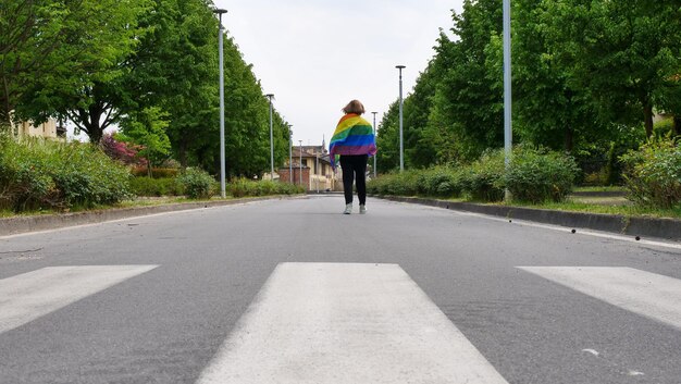 Femme lesbienne avec drapeau LGBT sur la route du ciel