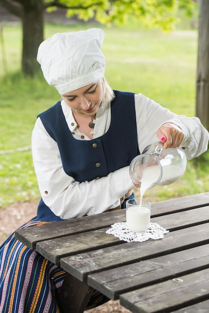 Femme lettone en costume traditionnel avec verre de lait sur la nature