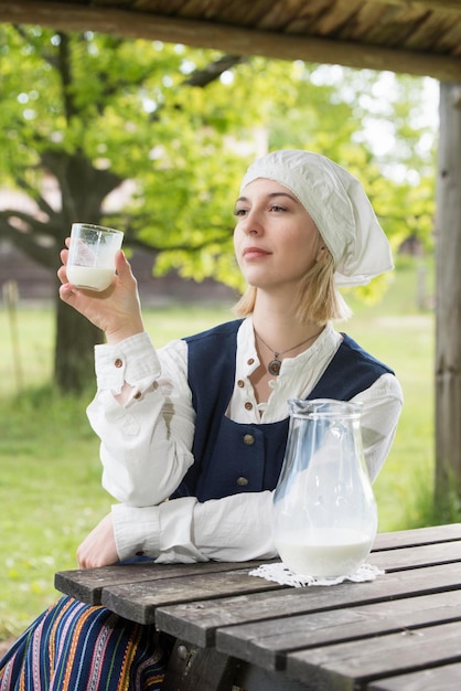 Femme lettone en costume traditionnel avec verre de lait sur la nature