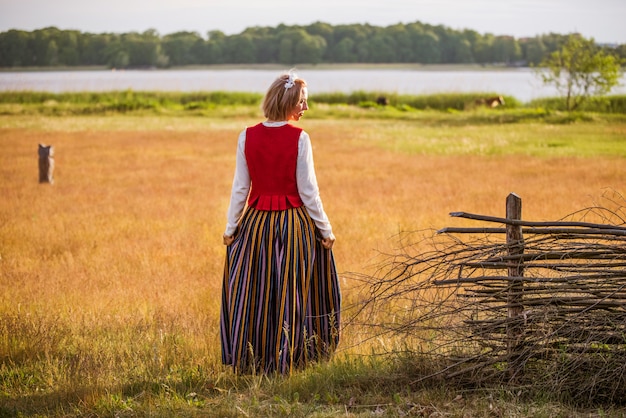 Femme lettone en vêtements traditionnels dans le champ